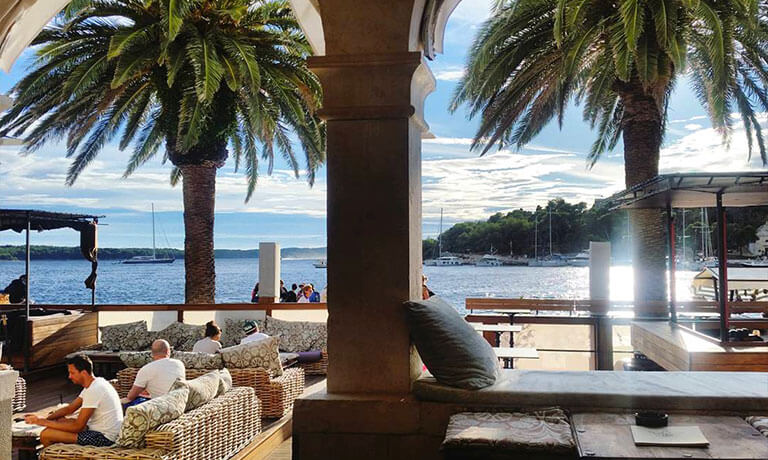 people sitting on a bench by the beach