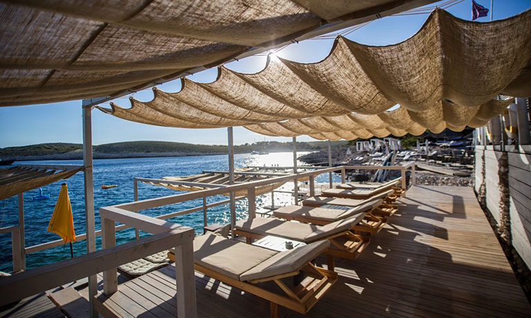 a deck with umbrellas and chairs on it by the water