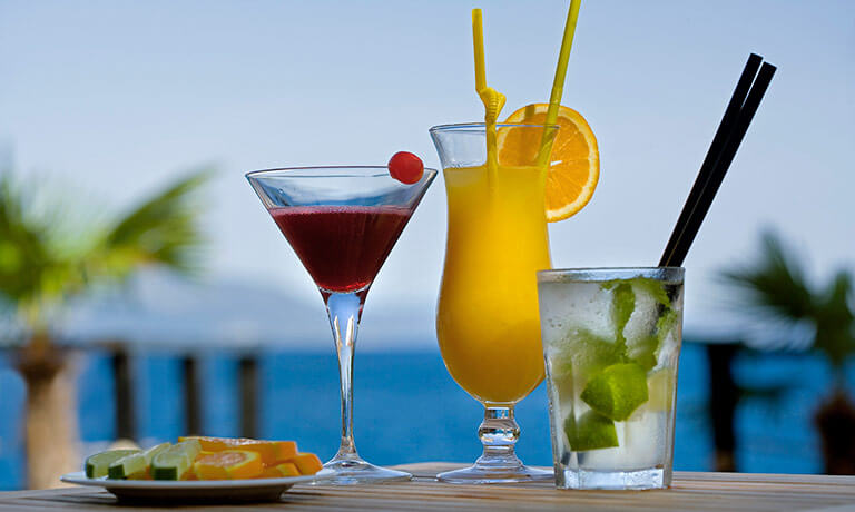 a group of drinks with fruit and straws on a table