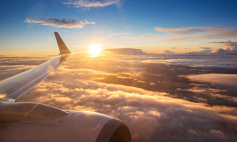 Der Flügel eines Flugzeugs am Himmel und darunter Wolken