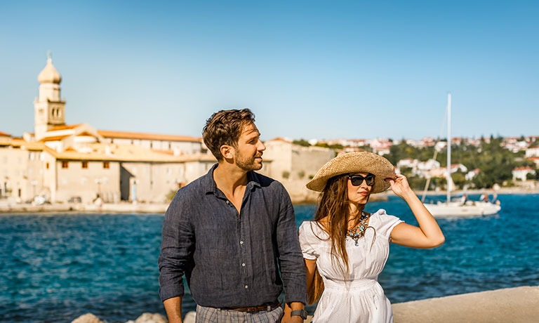 a man and woman standing next to each other and looking at the water