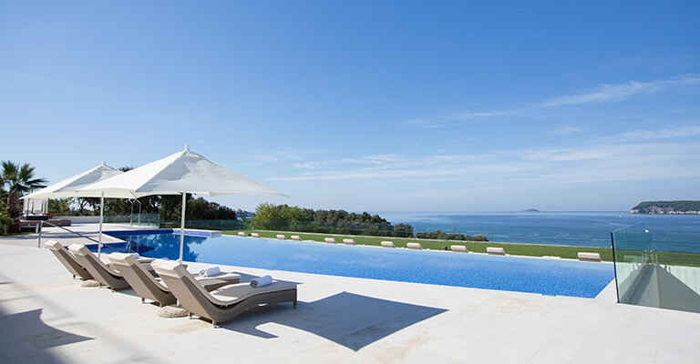 a pool with lounge chairs and umbrellas by the water