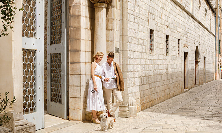 a man and woman standing in front of a building with a dog