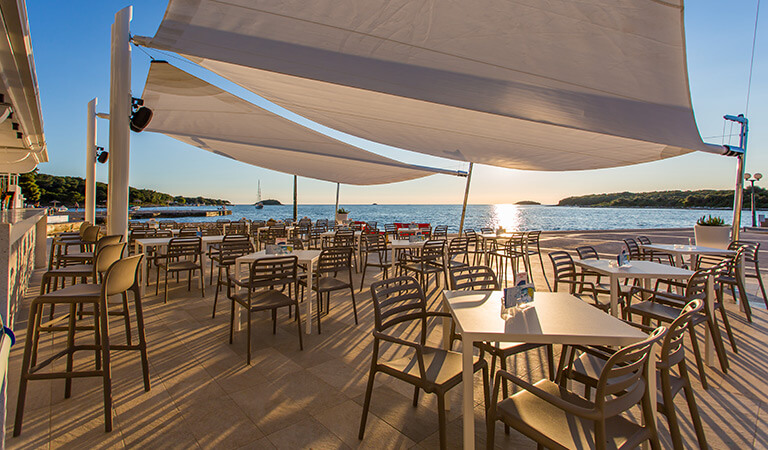 a deck with tables and chairs on it by the sea