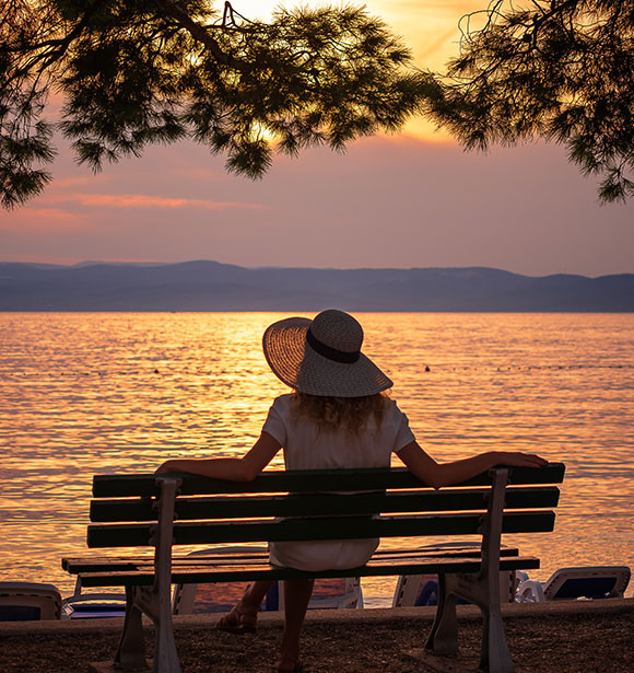 a person sitting on a bench looking at the water