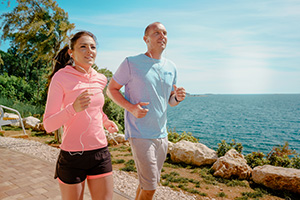 a man and a woman jogging by the coast