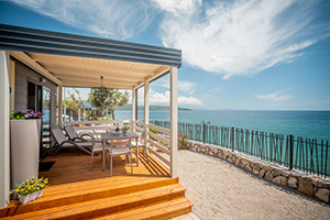 a deck with tables and chairs on it by the water